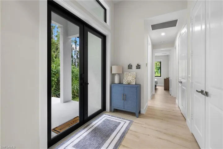 Entryway featuring double glass-panel doors with black frames, transom window, recessed lighting, and wood-finish flooring