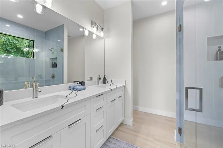Modern bathroom featuring a dual vanity with white cabinetry, integrated sinks, and a stone-finish countertop