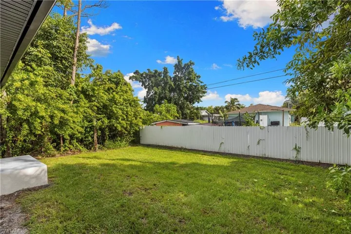 Expansive green lawn framed by a privacy fence and mature trees