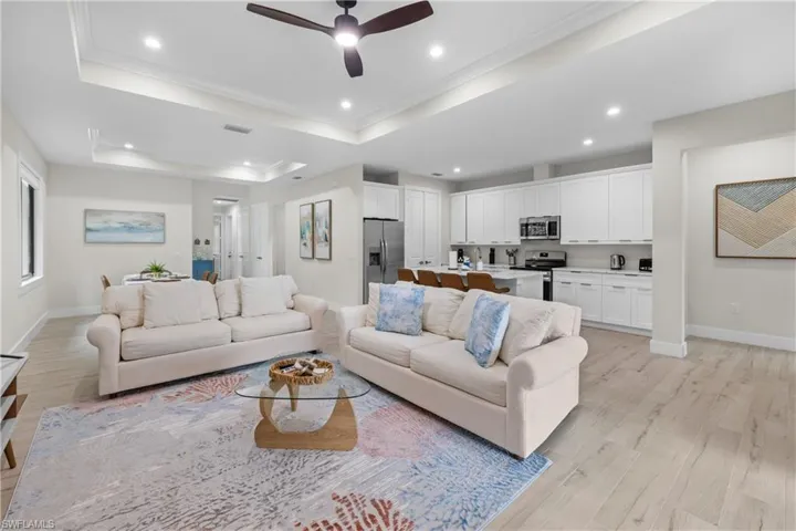 Open-concept living area with wood-finish flooring, a tray ceiling, and recessed lighting