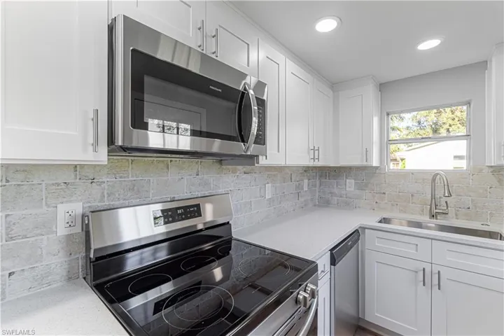 Kitchen with white cabinetry, sink, appliances with stainless steel finishes, and tasteful backsplash