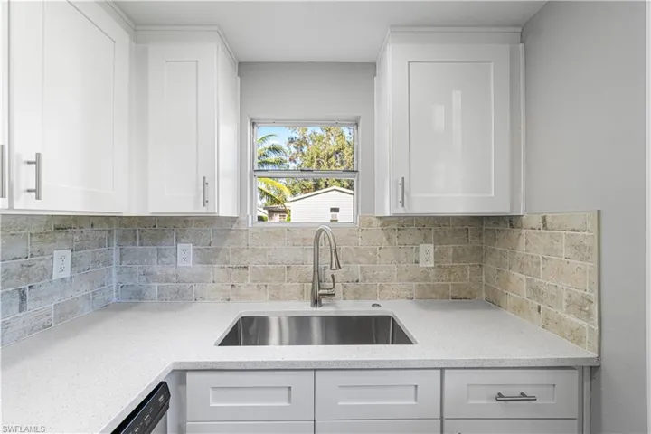 Kitchen with tasteful backsplash, dishwasher, sink, and white cabinets