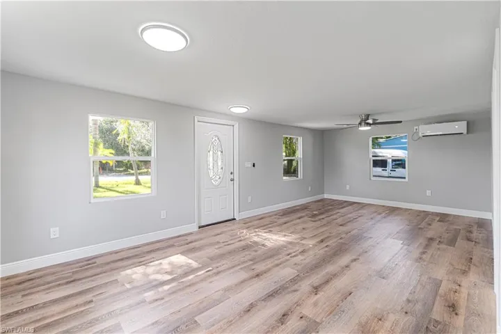 Entryway with light hardwood / wood-style floors, an AC wall unit, a wealth of natural light, and ceiling fan