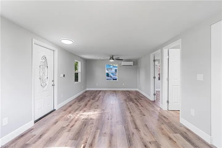 Foyer featuring light wood-type flooring, a wall unit AC, and ceiling fan