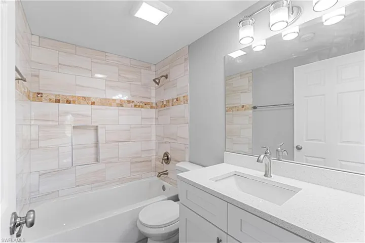 Full bathroom with vanity, tiled shower / bath combo, and toilet