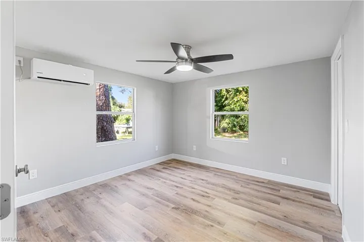 Empty room featuring plenty of natural light, ceiling fan, light hardwood / wood-style flooring, and a wall mounted AC