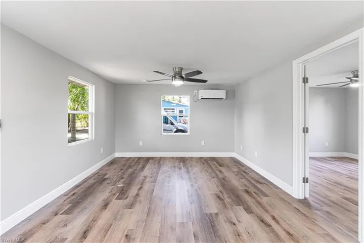 Unfurnished room with a wall unit AC, ceiling fan, and light wood-type flooring