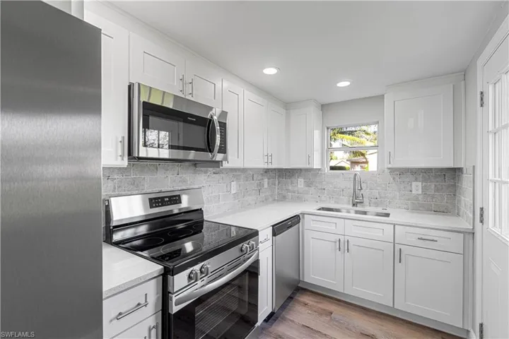 Kitchen with white cabinetry, sink, light wood-type flooring, and appliances with stainless steel finishes
