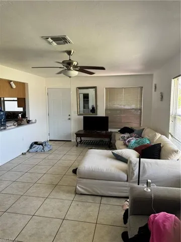 Living area featuring visible vents, light tile patterned floors, and ceiling fan