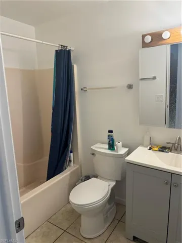 Bathroom featuring tile patterned floors, shower / bath combination with curtain, toilet, and vanity