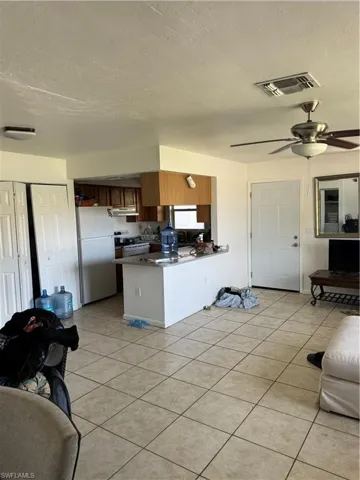 Kitchen with exhaust hood, light tile patterned flooring, visible vents, a peninsula, and refrigerator