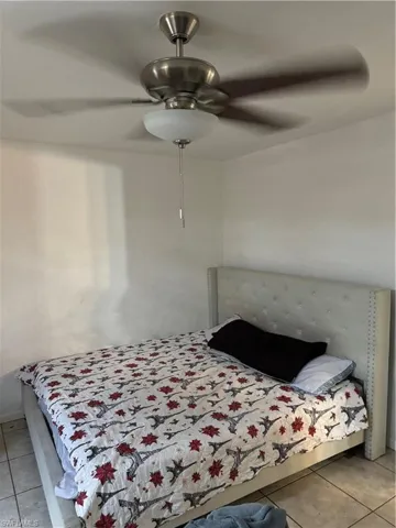 Tiled bedroom with a ceiling fan