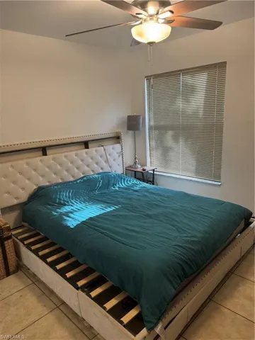 Tiled bedroom featuring ceiling fan