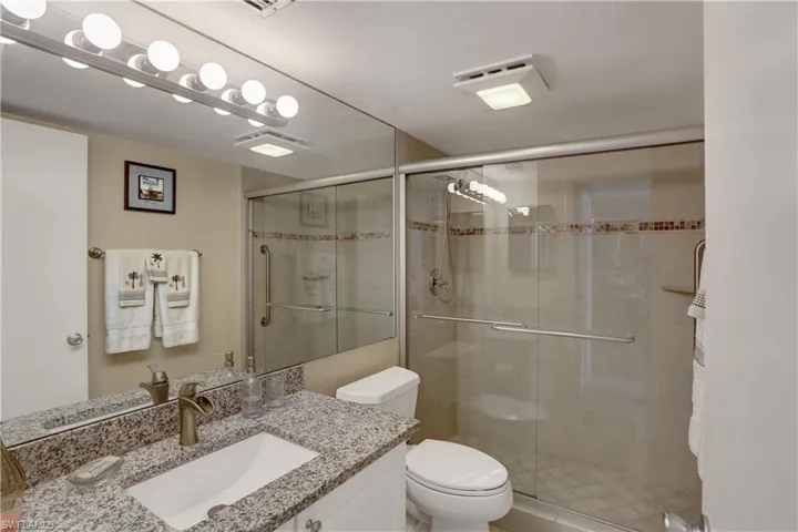 Bathroom with toilet, vanity, and an enclosed shower