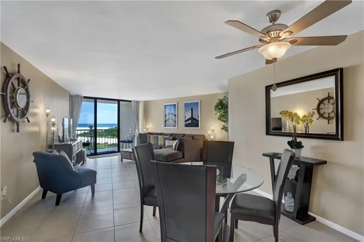 Tiled dining space with floor to ceiling windows and ceiling fan