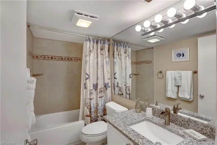 Full bathroom featuring vanity, toilet, a textured ceiling, and shower / bath combination with curtain