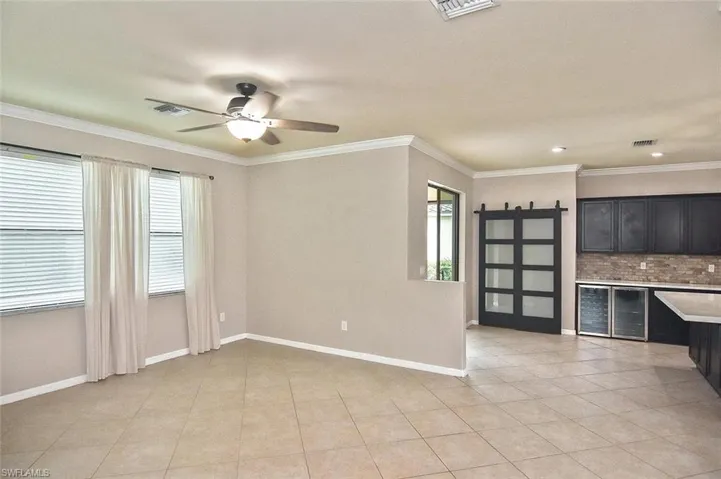 Unfurnished living room featuring crown molding, light tile patterned floors, and a ceiling fan