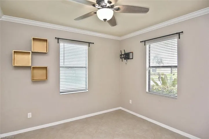 Empty room featuring ornamental molding, plenty of natural light, and ceiling fan