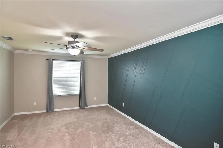 Primary bedroom featuring ornamental molding, light carpet, and ceiling fan