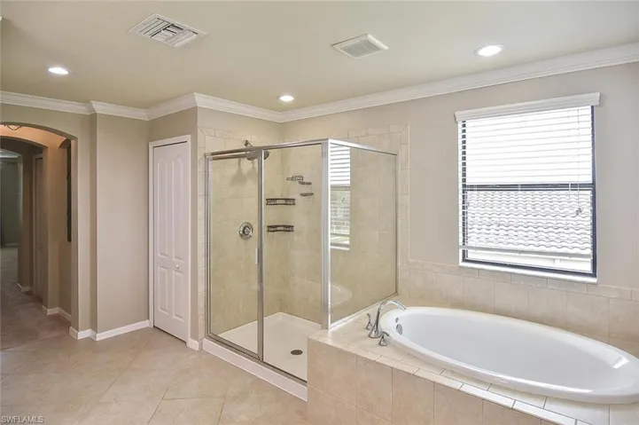 Full bath with a stall shower, a garden tub, ornamental molding, healthy amount of natural light, and light tile patterned flooring