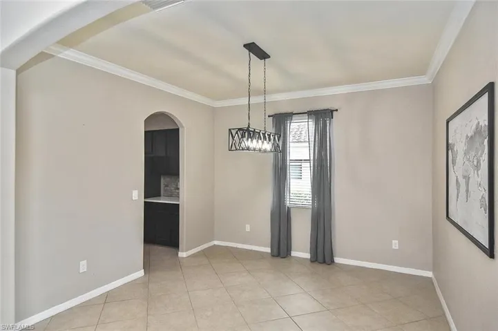 Unfurnished dining area featuring arched walkways, crown molding, and light tile patterned floors