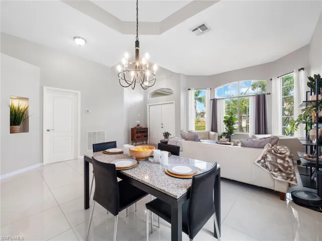 Dining area with a tray ceiling, hanging lights, and light tile patterned flooring