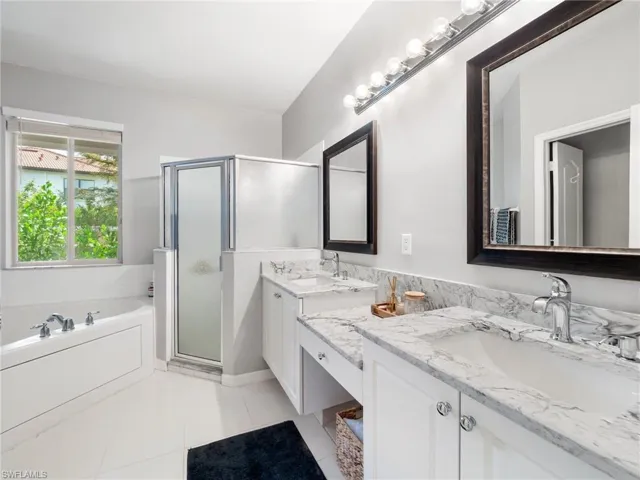 Bathroom with double vanity, a garden tub, a shower stall, and light tile patterned flooring