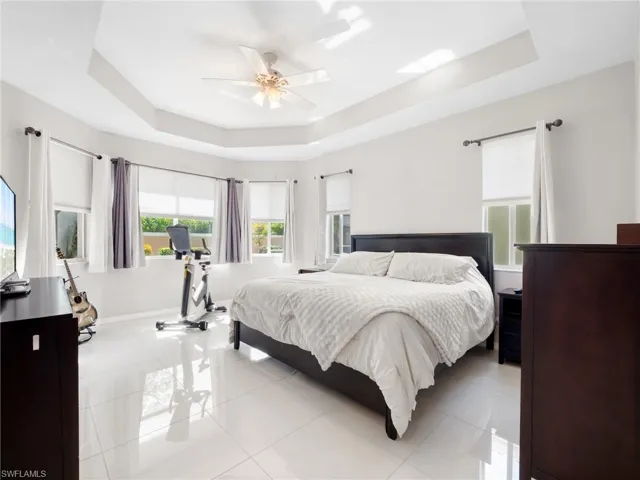 Bedroom featuring a raised ceiling, tile patterned flooring, and a ceiling fan