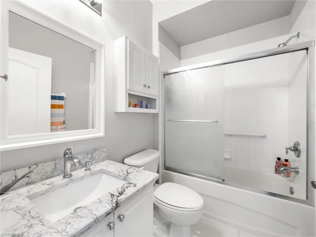 Bathroom featuring vanity and bath / shower combo with glass door