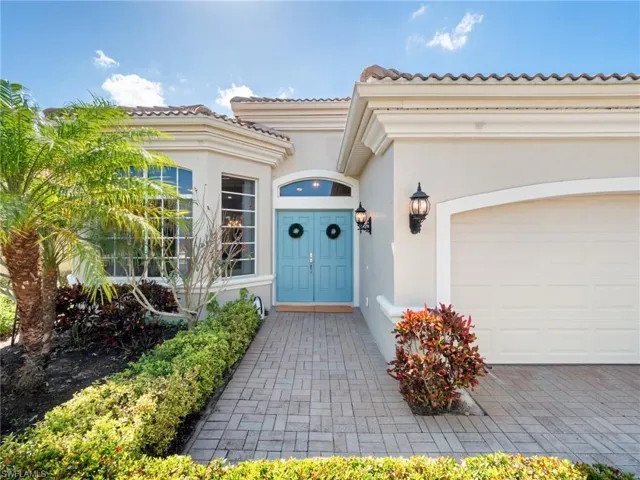 Doorway to property featuring a garage, stucco siding, a tiled roof, and driveway
