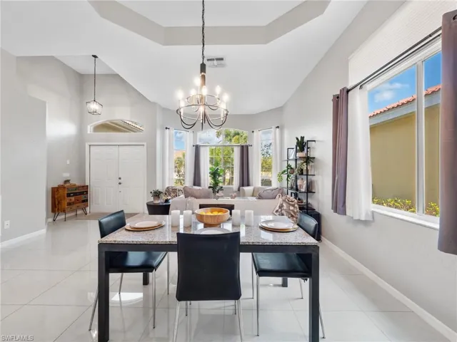 Dining room with a raised ceiling, a chandelier, and light tile patterned floors