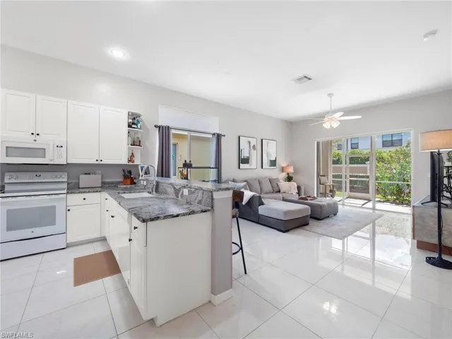 Kitchen featuring white appliances, a peninsula, a breakfast bar area, white cabinets, and open floor plan