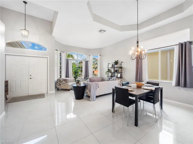 Dining area with a chandelier, a tray ceiling, and light tile patterned floors