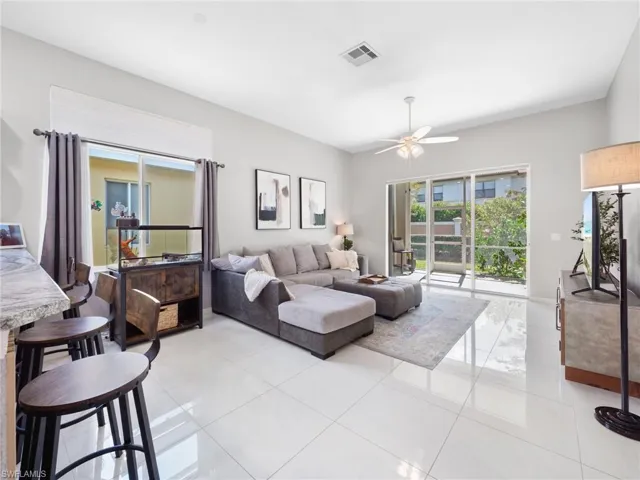 Living room with a ceiling fan, plenty of natural light, and light tile patterned floors