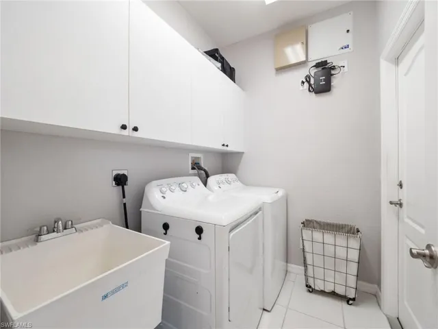 Laundry area featuring cabinet space, washing machine and clothes dryer, and light tile patterned flooring