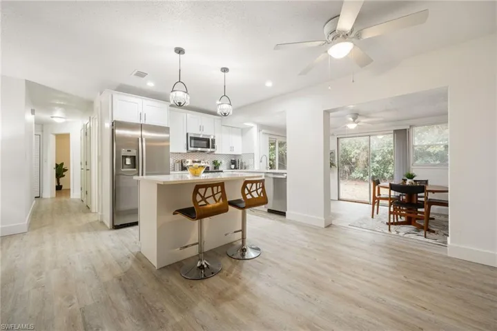 Kitchen with appliances with stainless steel finishes, a kitchen island, light wood-type flooring, baseboards, and recessed lighting