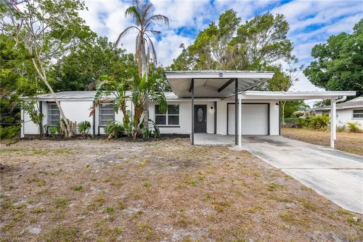 Mid-century home featuring an attached garage, stucco siding, and driveway