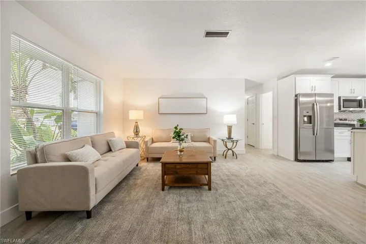 Living area featuring light wood finished floors, baseboards, and a textured ceiling