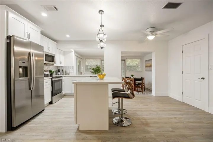 Kitchen featuring stainless steel appliances, light countertops, a breakfast bar area, a kitchen island, and light wood finished floors