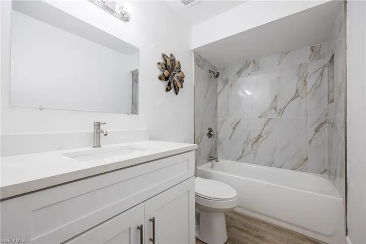 Full bathroom with vanity, wood finished floors, shower / washtub combination, and toilet