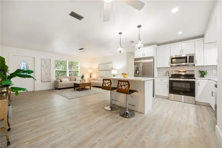 Kitchen featuring appliances with stainless steel finishes, light wood-style floors, a breakfast bar area, tasteful backsplash, and open floor plan
