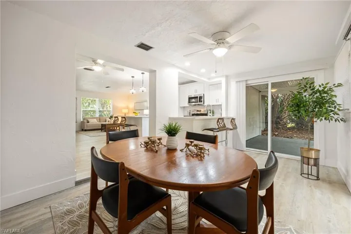 Dining area featuring ceiling fan, light wood-style floors, baseboards, and a textured ceiling