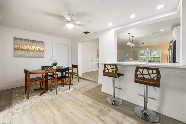 Dining space featuring light wood-type flooring, ceiling fan, baseboards, recessed lighting, and a chandelier