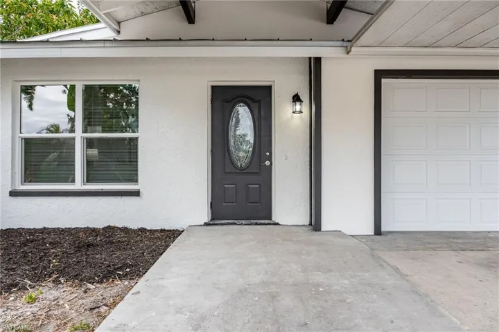 Entrance to property with stucco siding and concrete driveway