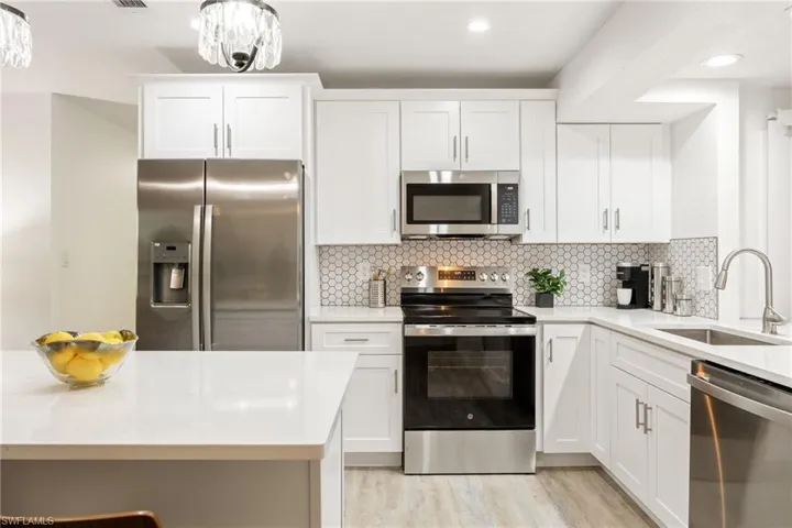 Kitchen featuring stainless steel appliances, a sink, light countertops, and recessed lighting