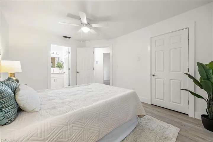 Bedroom with light wood finished floors, ceiling fan, connected bathroom, and baseboards