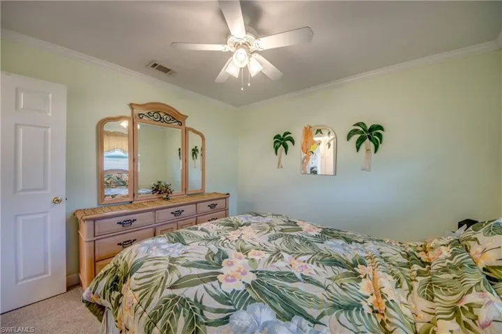 Bedroom featuring ornamental molding, light carpet, and ceiling fan