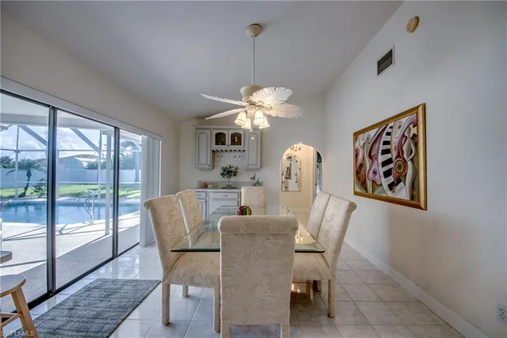 Dining room with vaulted ceiling, light tile patterned floors, arched walkways, and ceiling fan