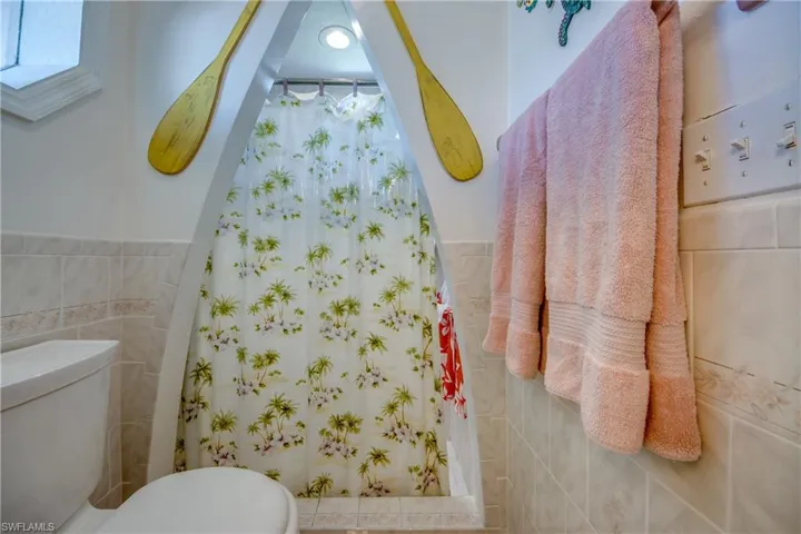 Bathroom featuring tile walls, a shower with curtain, and a wainscoted wall