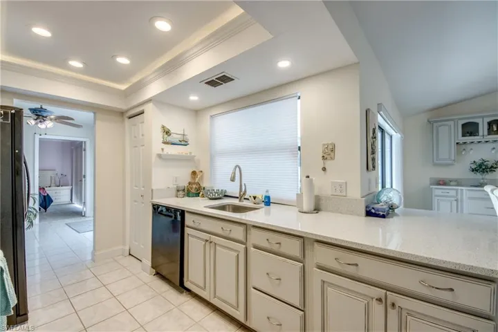 Kitchen with dishwasher, freestanding refrigerator, light tile patterned floors, ornamental molding, and recessed lighting